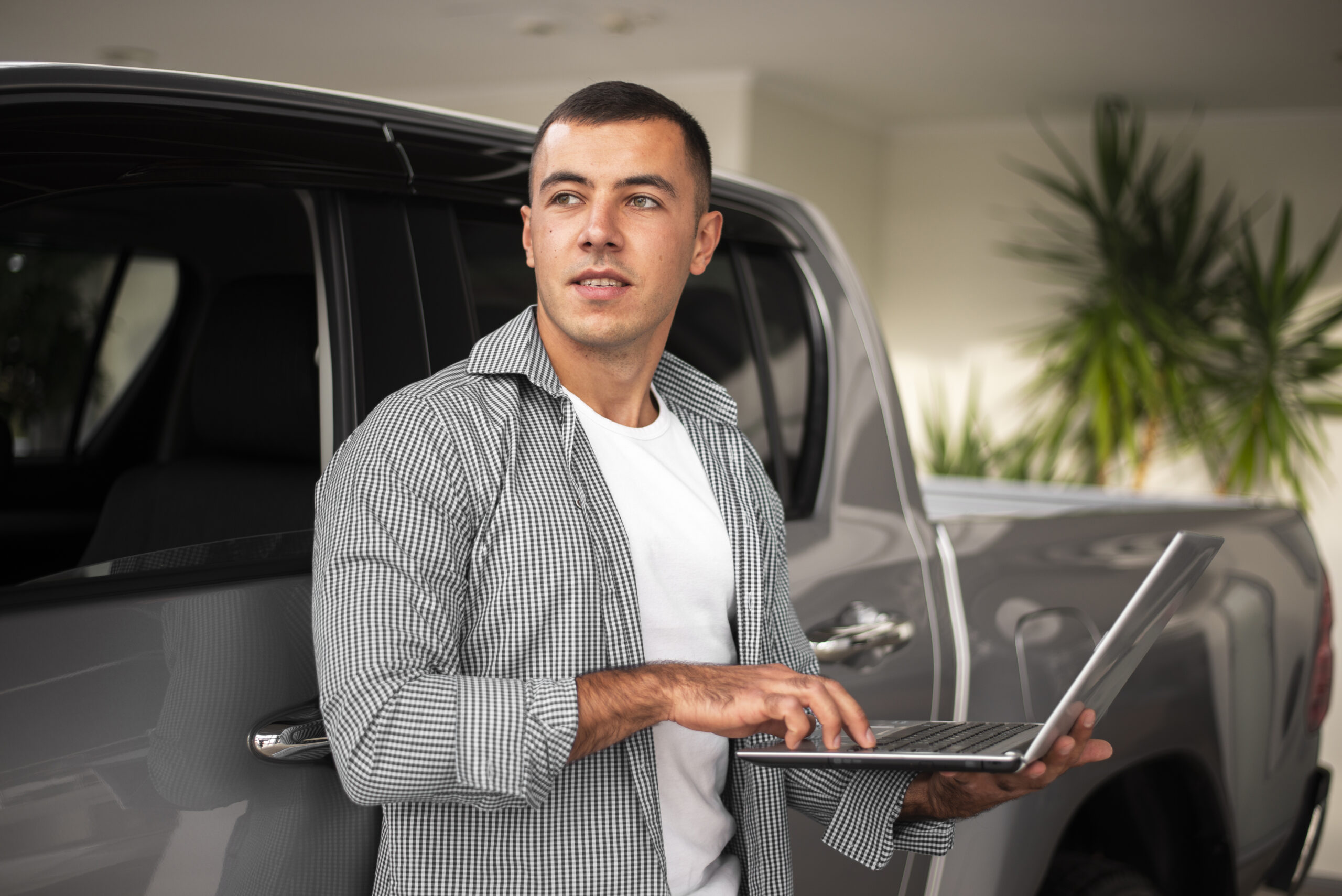 a handsome young man measuring used car metrics on his laptop