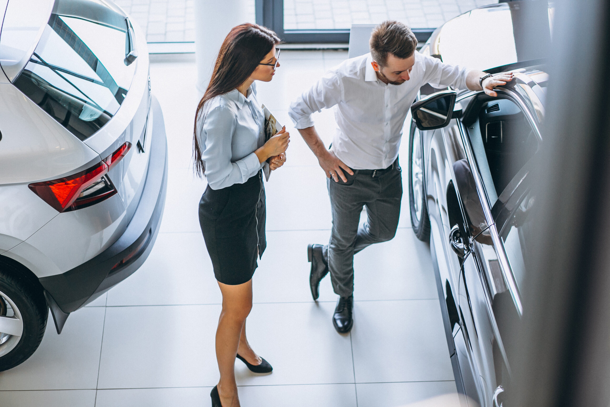 Car dealer setting pricing strategies using data-driven tools on a laptop.